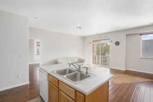 Kitchen featuring dishwasher, sink, a center island with sink, and dark hardwood / wood-style floors