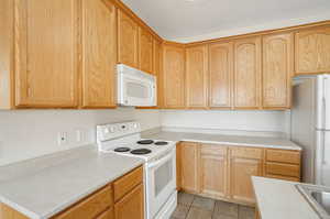 Kitchen featuring a textured ceiling, white appliances, and light tile patterned floors