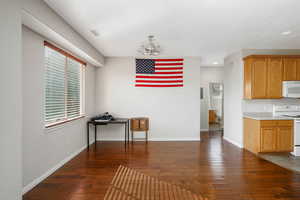 Kitchen with a notable chandelier, white appliances, and dark hardwood / wood-style flooring