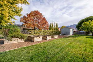 View of backyard featuring garden boxes, storage shed and a mountain view