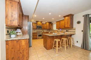 Kitchen featuring kitchen peninsula, decorative backsplash, stainless steel appliances, and a breakfast bar area