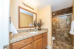 Bathroom with vanity, an enclosed shower, a textured ceiling, and toilet