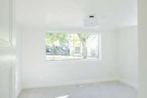 Spare room featuring light carpet and plenty of natural light