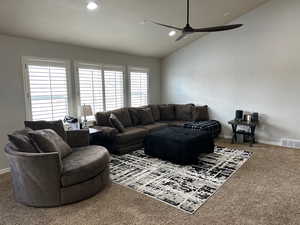 Carpeted living room with vaulted ceiling and ceiling fan