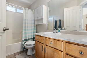 Full bathroom with vanity, shower / tub combo with curtain, toilet, and tile patterned floors