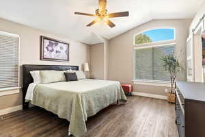 Bedroom with dark hardwood / wood-style flooring, lofted ceiling, and ceiling fan