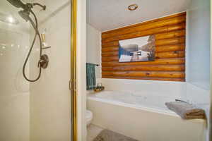 Bathroom with toilet, a textured ceiling, and independent shower and bath