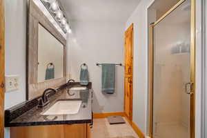 Bathroom with vanity, a textured ceiling, a shower with shower door, and tile patterned floors