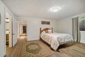 Bedroom with light hardwood / wood-style floors, a textured ceiling, and ensuite bathroom