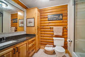 Bathroom featuring toilet, walk in shower, a textured ceiling, and rustic walls