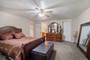 Carpeted bedroom with connected bathroom, a textured ceiling, and ceiling fan