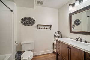 Full bathroom featuring hardwood / wood-style flooring, toilet, tub / shower combination, vanity, and a textured ceiling