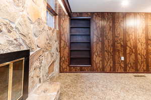 Unfurnished living room featuring wood walls, carpet, and built in shelves