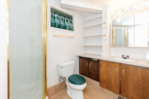 Bathroom featuring a shower with door, toilet, tile patterned flooring, and vanity