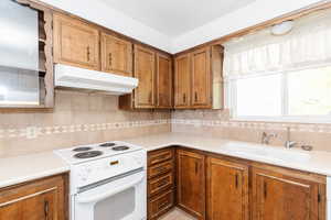 Kitchen with sink, white stove, and tasteful backsplash