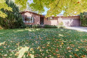 Single story home with a garage and a front lawn