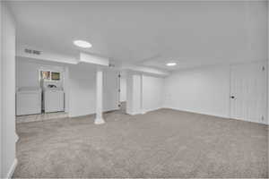 Basement with washing machine and dryer and light colored carpet