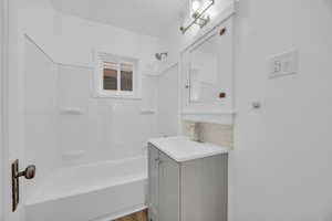 Bathroom featuring vanity, wood-type flooring, washtub / shower combination, and backsplash