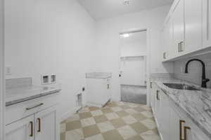 Interior space featuring light stone countertops, sink, white cabinets, and backsplash