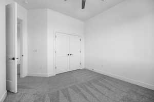 Unfurnished bedroom with carpet floors, a closet, and ceiling fan