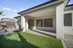 Back of house with a patio and a lawn