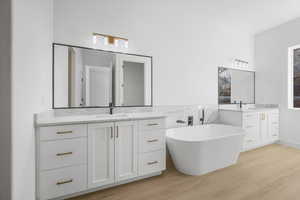 Bathroom featuring vanity, wood-type flooring, and a bath