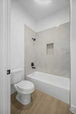 Bathroom with toilet and tiled shower / bath combo