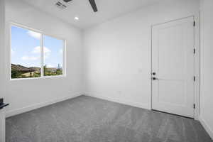 Unfurnished room with dark carpet, a healthy amount of sunlight, and ceiling fan