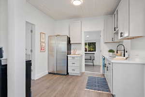 Kitchen featuring appliances with stainless steel finishes, light hardwood / wood-style flooring, white cabinetry, and wooden ceiling