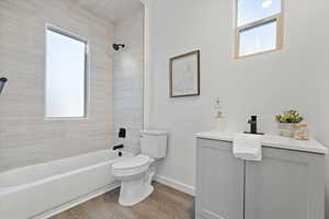 Full bathroom featuring vanity, tiled shower / bath, hardwood / wood-style flooring, and toilet