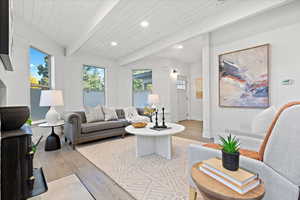 Living room with beamed ceiling, wood ceiling, light wood-type flooring, and a healthy amount of sunlight