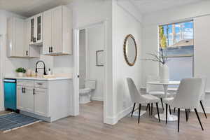 Kitchen featuring wood ceiling, light hardwood / wood-style flooring, sink, stainless steel dishwasher, and white cabinets