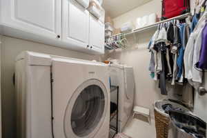 Laundry room with cabinets, independent washer and dryer, and light tile patterned floors