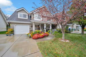 View of front of home with a garage, a front yard, and a porch