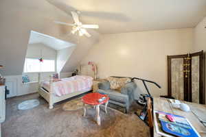 Carpeted bedroom featuring vaulted ceiling and ceiling fan