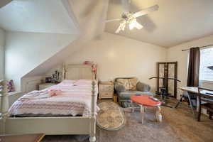 Carpeted bedroom with ceiling fan and vaulted ceiling