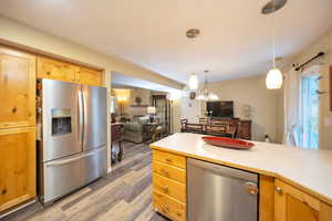 Kitchen with pendant lighting, appliances with stainless steel finishes, and hardwood / wood-style flooring