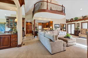 Living room off kitchen featuring French doors, light carpet, a healthy amount of sunlight, and a fireplace