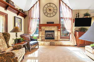 Living room off kitchen featuring French doors, light carpet, a healthy amount of sunlight, and a fireplace