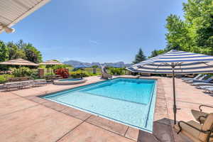 View of pool with an in ground hot tub, a water slide, a Kolob mountain view, and lounge area