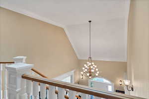 Staircase to level 2 and basement, lofted ceiling with skylight, ornamental molding, and a chandelier