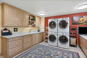 Laundry room featuring stacked washer / drying machine, cabinets, sewing area and wrapping area