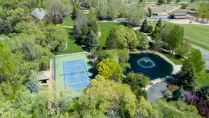 Aerial view featuring tennis/pickleball courts and pond