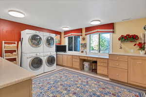 Laundry room featuring stacked washer / drying machine, cabinets, sewing area and wrapping area