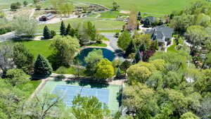 Aerial view featuring tennis/pickleball courts and pond