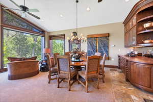 Dining space off kitchen and living room high vaulted ceiling and ceiling fan with notable chandelier