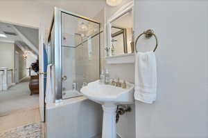 Bathroom off spare bedrooms with toilet, tile patterned floors, and a shower with door