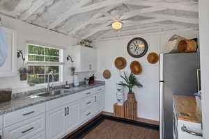 Garden shed kitchen featuring sink, lofted ceiling with beams, white cabinetry, and refrigerator