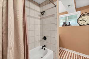 Bathroom with shower / tub combo, a textured ceiling, and tile patterned flooring