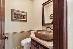 Bathroom with vanity and toilet off living room and kitchen